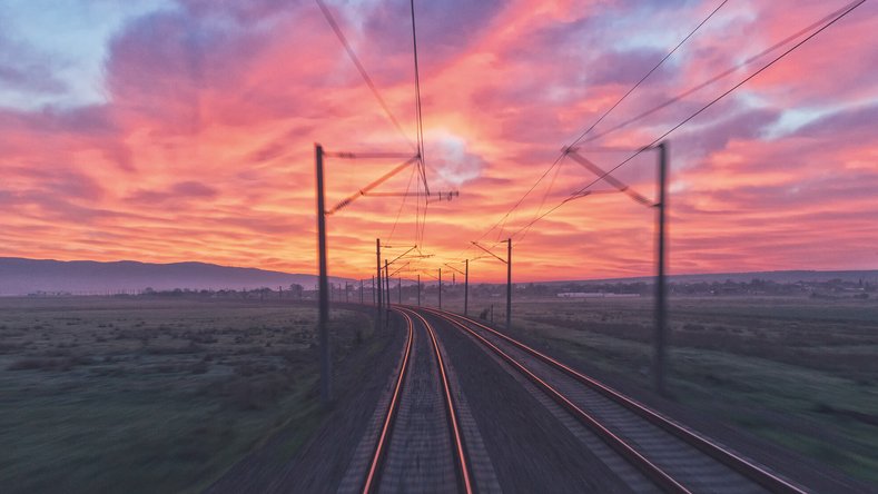 Twin railway tracks at sunset with red and orange sky