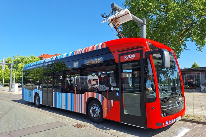 An RVM red bus is parked at the charging station