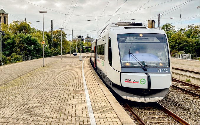 A white Regiobahn train arrives at a station.