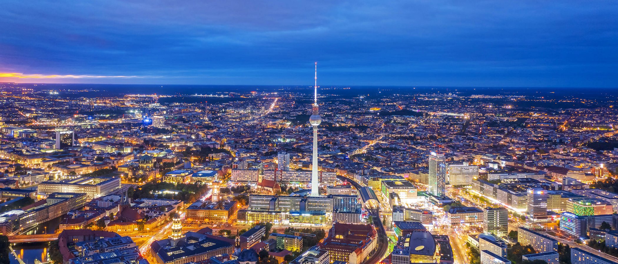 Aerial view of Berlin at night with illuminated TV tower and transport infrastructure
