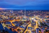 Luftaufnahme von Berlin bei Nacht mit beleuchtetem Fernsehturm und Verkehrsinfrastruktur