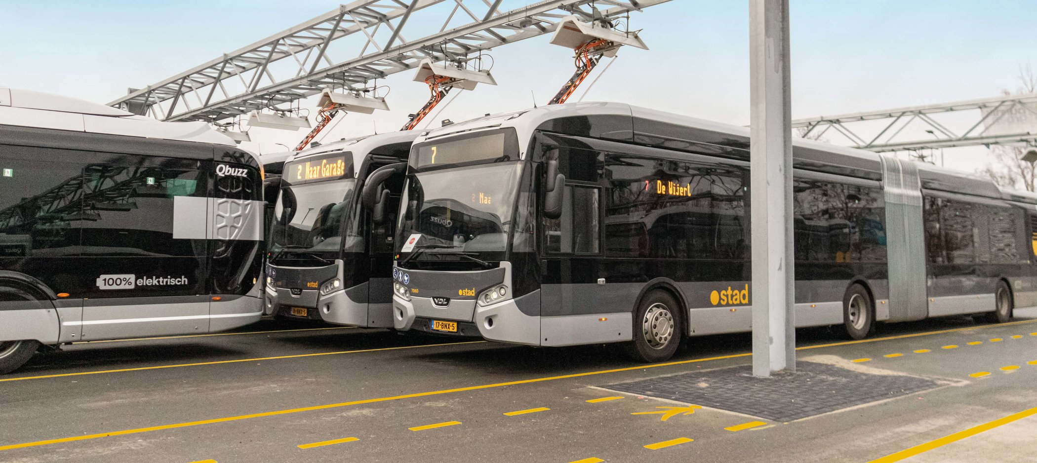 Electric buses charging under pantograph charging stations at a bus depot