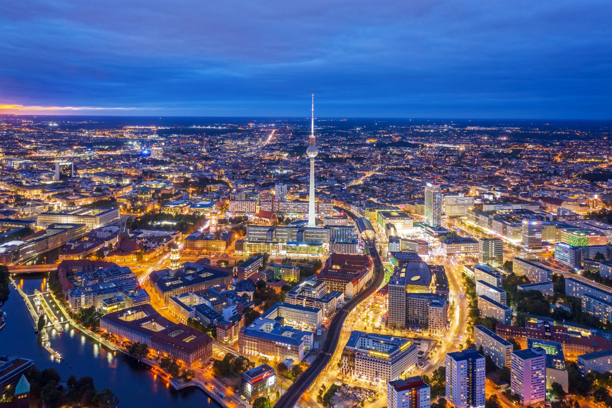 Aerial view of an illuminated city at night with TV tower and traffic infrastructure