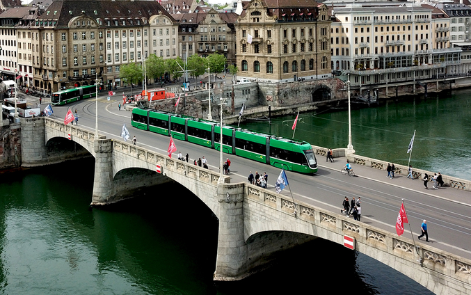 Green tram on a bridge over a river in Basel