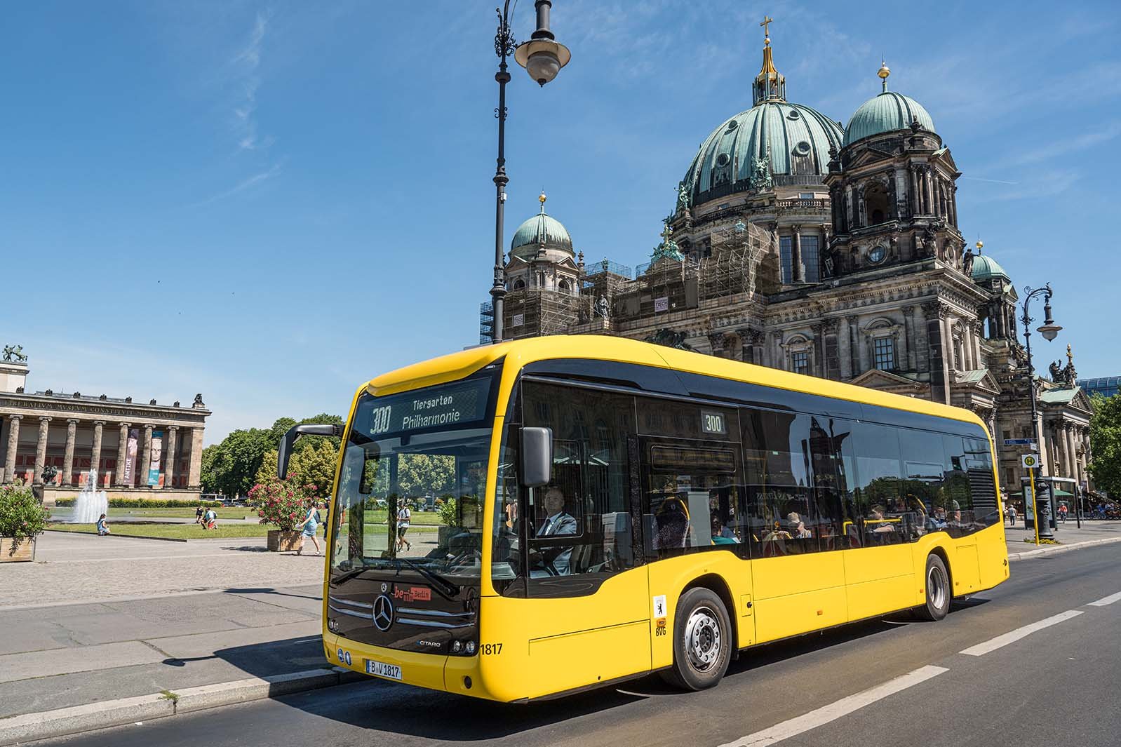 Yellow BVG bus driving along the Spree river in front of Berlin Cathedral