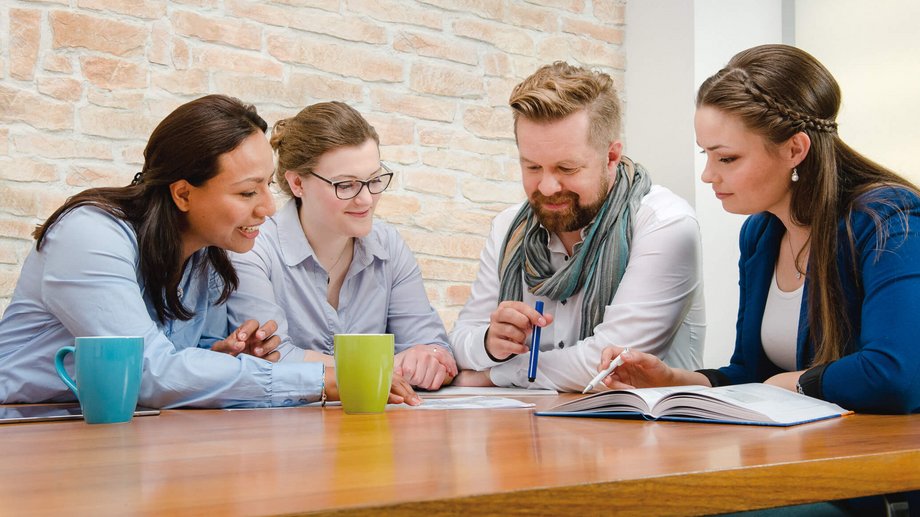 Drei Frauen und ein Mann sitzend bei einer Besprechung am Tisch