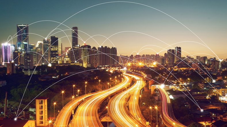 Skyline notturno con autostrade illuminate e nodi connessi come simbolo di mobilità digitale