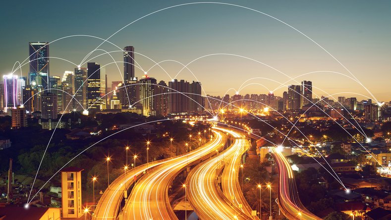 Skyline notturno con autostrade illuminate e nodi connessi come simbolo di mobilità digitale