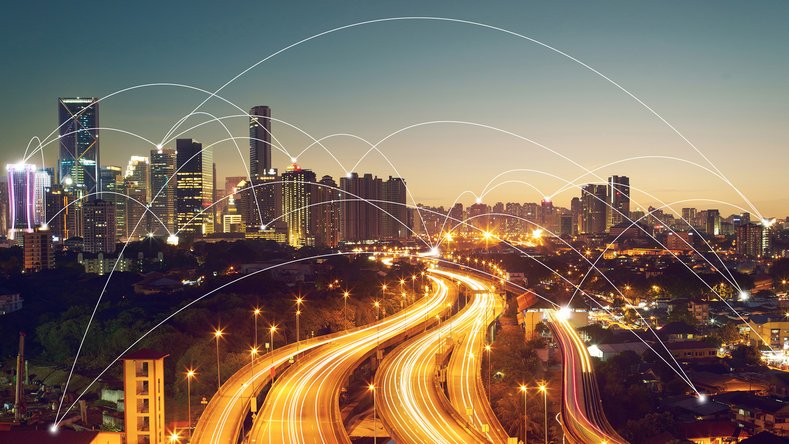 Horizonte urbano nocturno con autopistas iluminadas y nodos conectados como símbolo de movilidad digital
