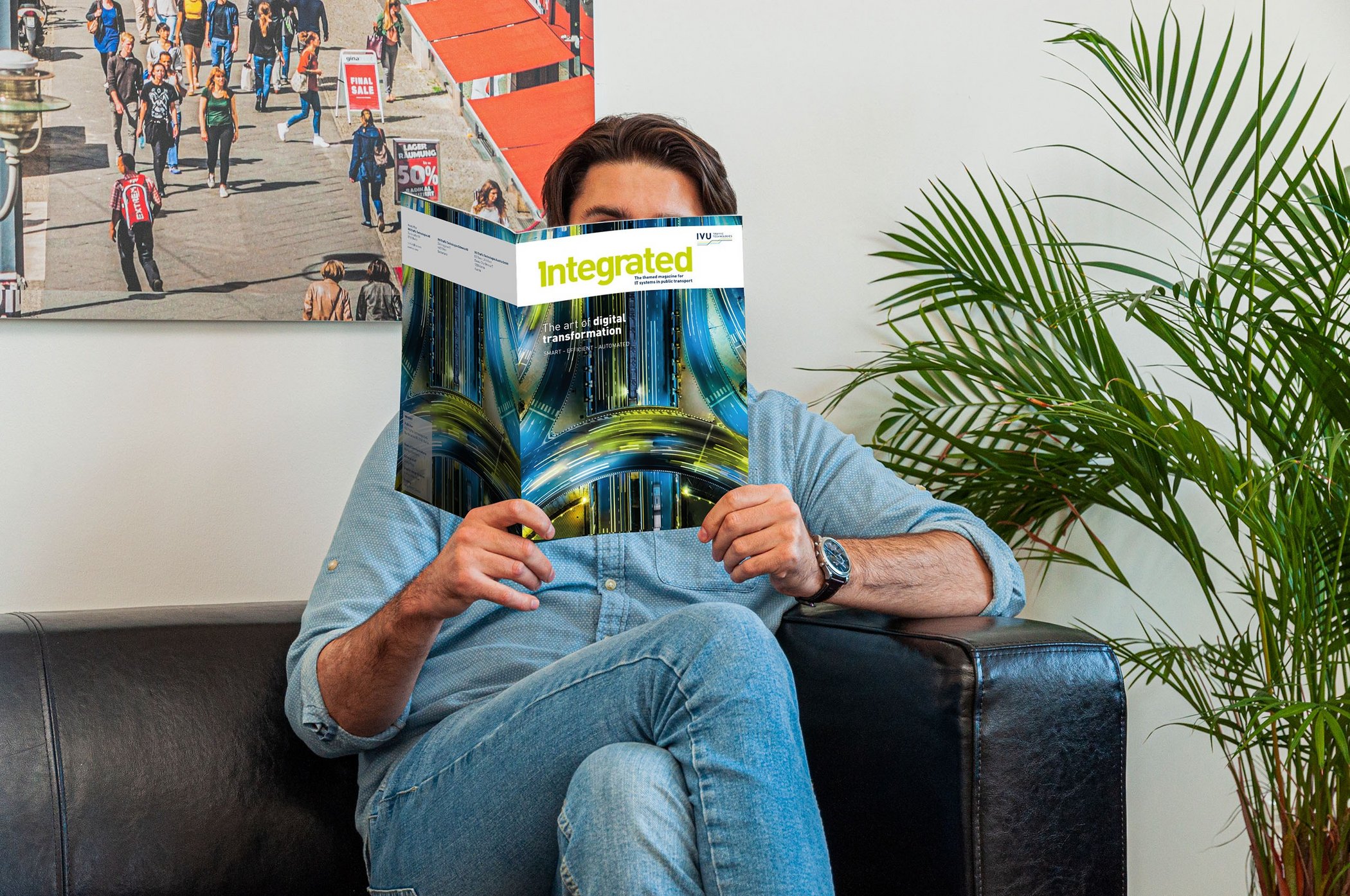 Man sitting on sofa reading IVU's "Integrated" magazine on digital transformation