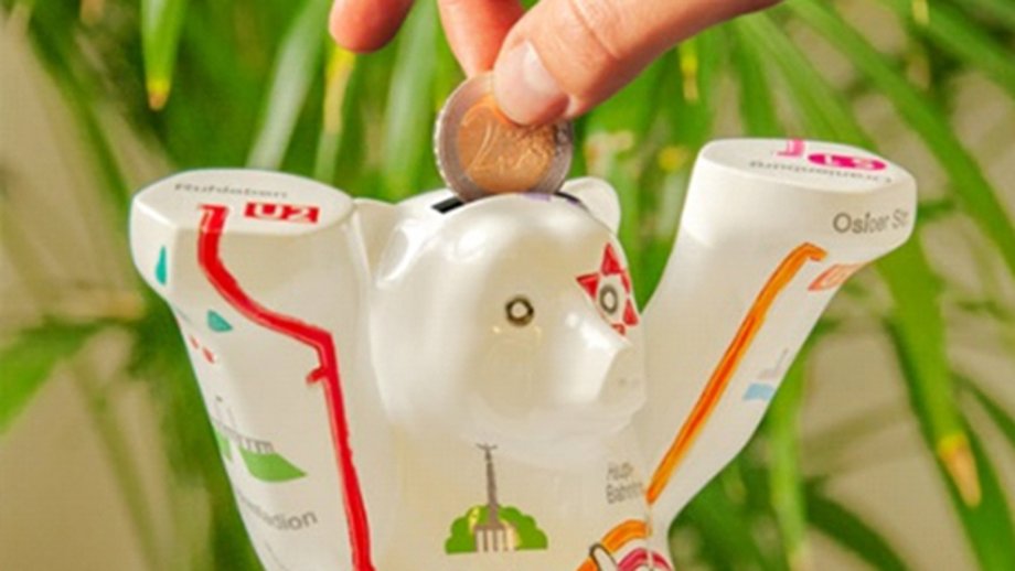 Hand putting a two-euro piece into a Berlin Bear money box