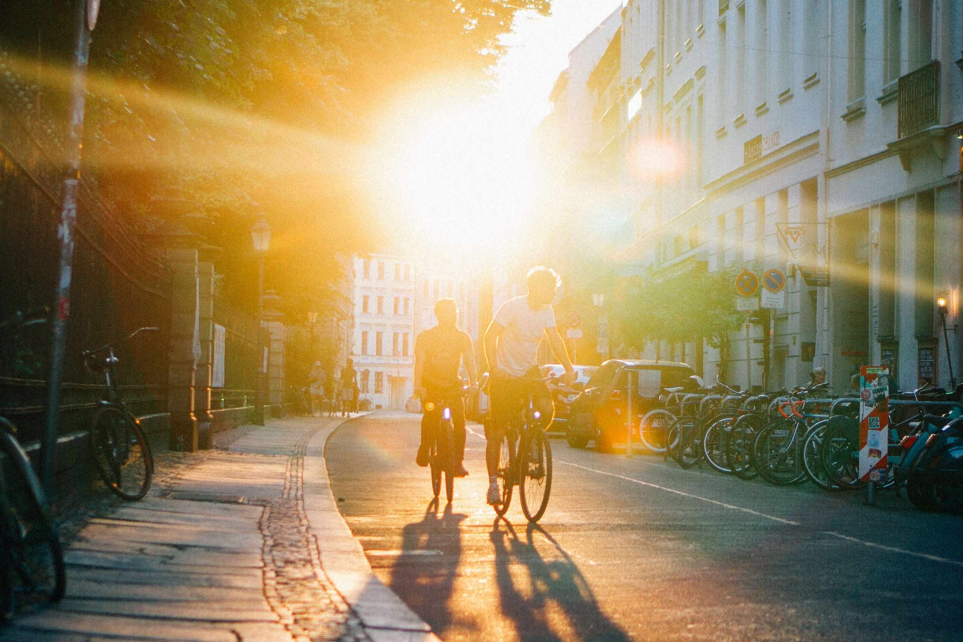 Two cyclists ride along the road at sunset