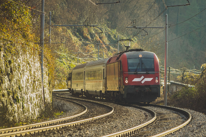 Red SZ railway in front of overgrown mountains