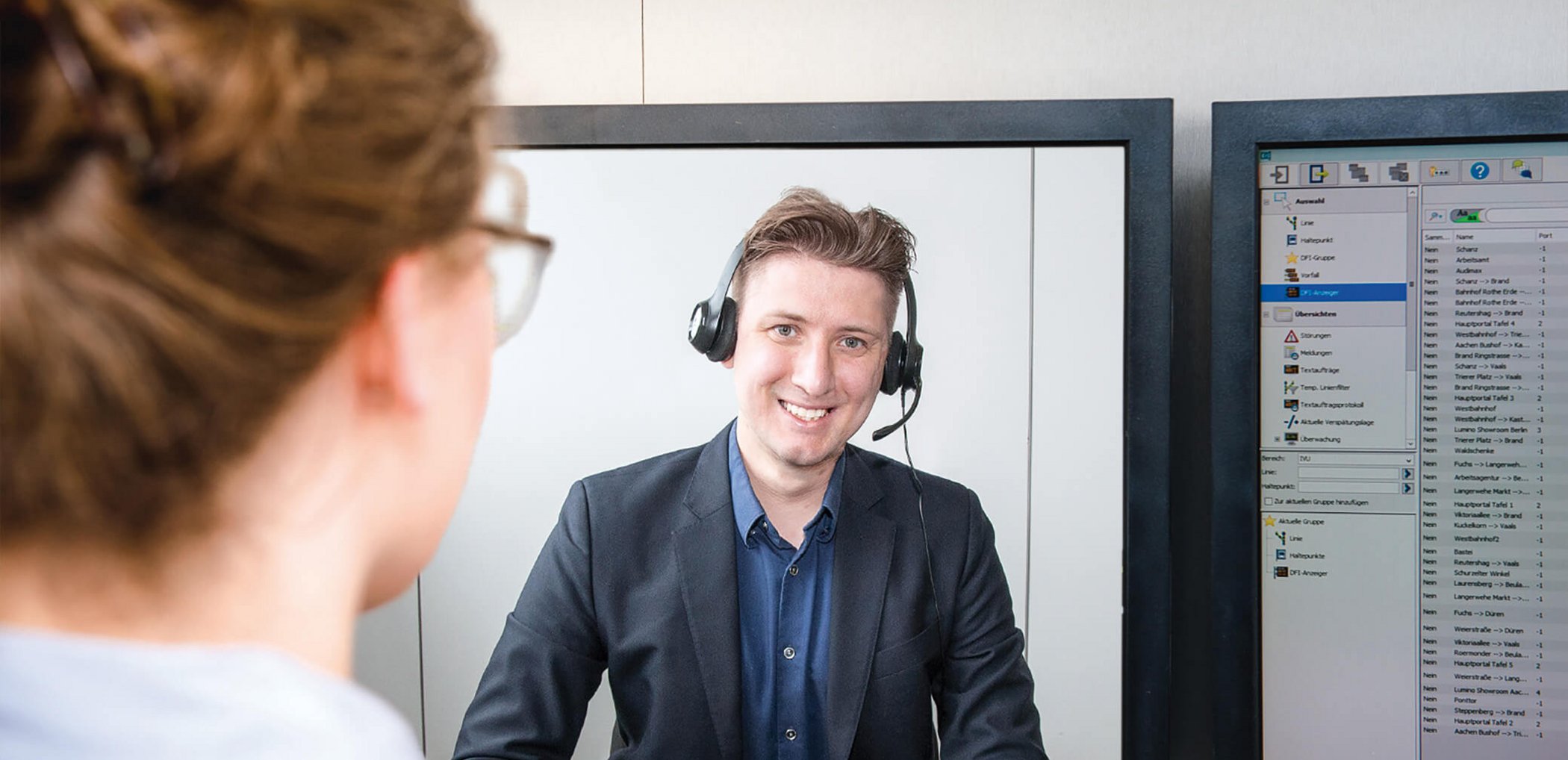 Employee in conversation with a smiling support agent via video conference on a monitor