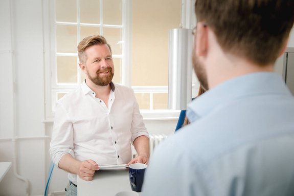Man from the front talking to a man seen from diagonally behind