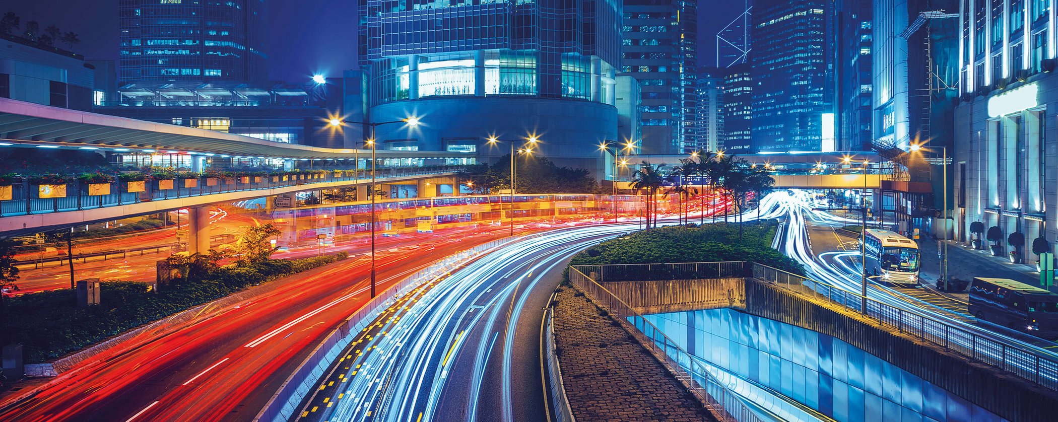 Night-time urban highway with traffic light trails and illuminated skyscrapers in the background