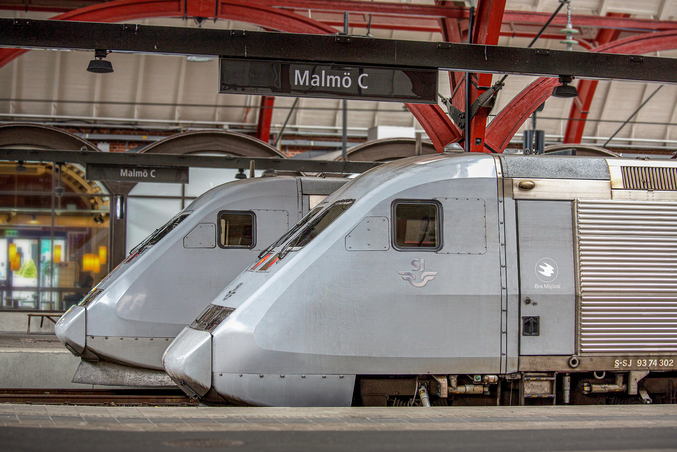Two silver-grey SJ trains stand on a railway track in Malmö.