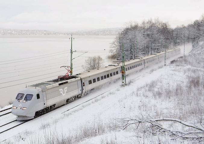 A grey-white SJ train in front of a snow landscape.