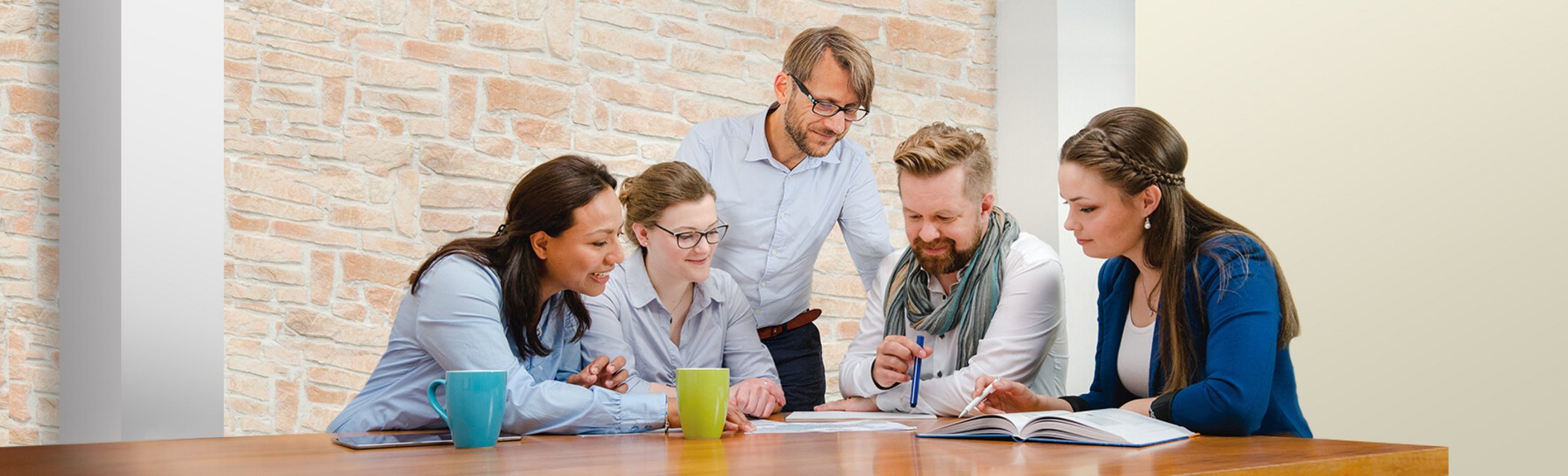 Five colleagues sit at a table and discuss the documents lying on it