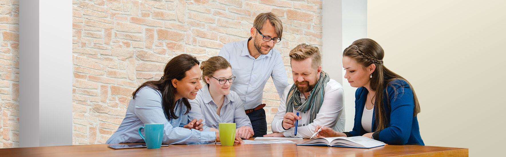 Five colleagues sit at a table and discuss the documents lying on it