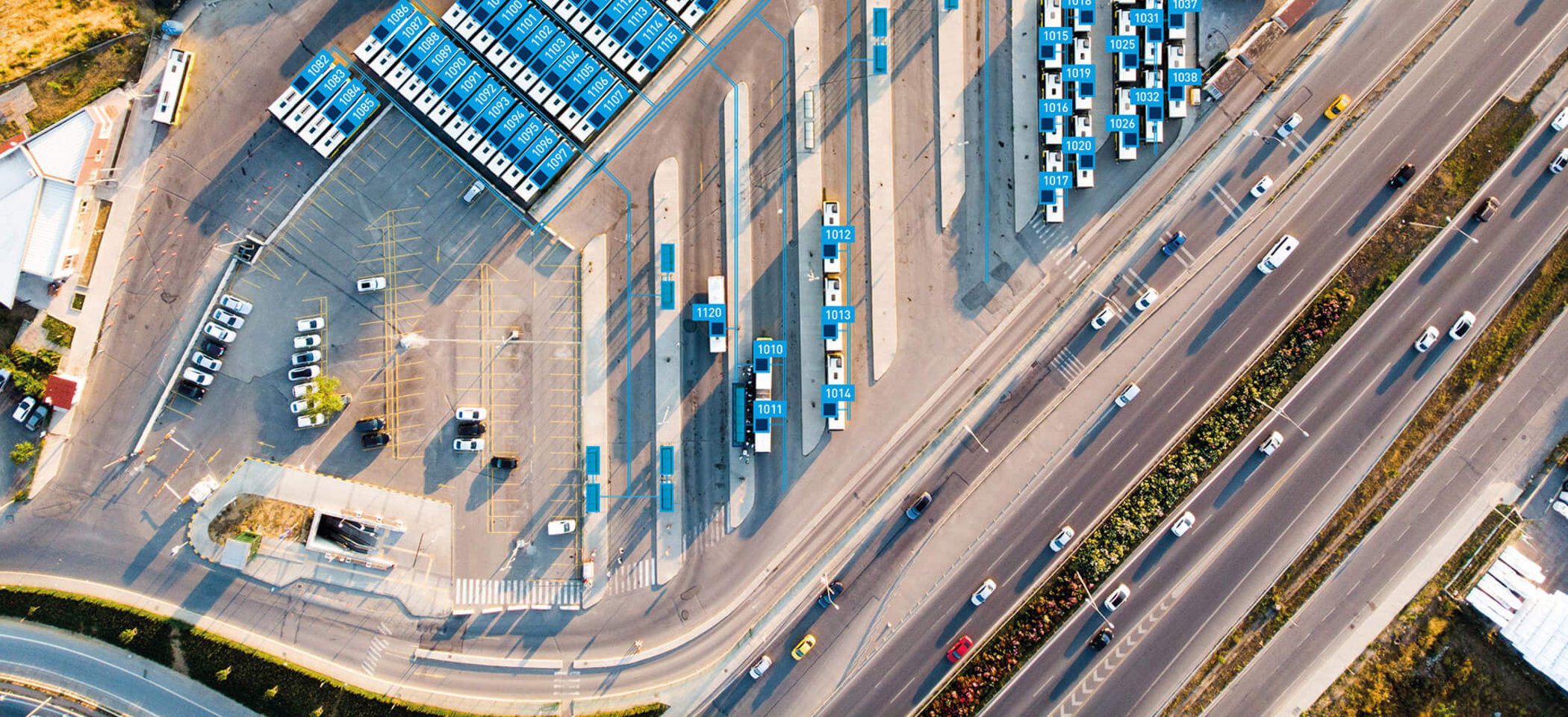 Aerial view of a bus depot with solar panels on hall roofs and parked buses
