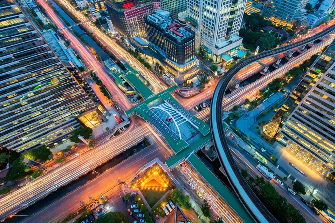Luftaufnahme eines Verkehrsknotenpunkts in Bangkok mit Straßenbahnhaltestelle und Lichtspuren