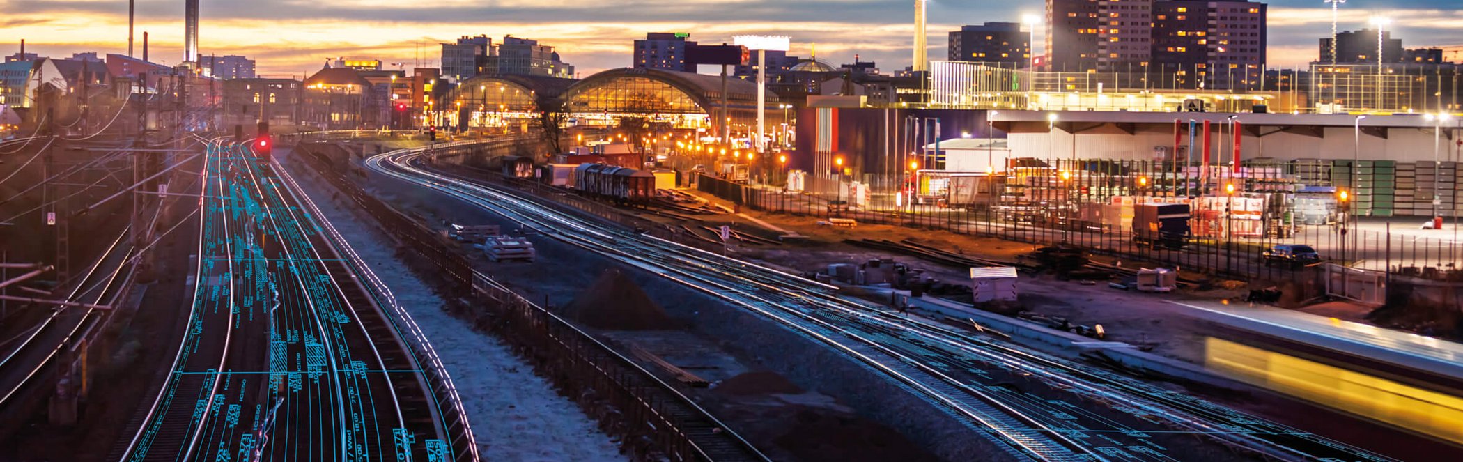 Berlin railway tracks at dusk with light trails from trains and TV tower in the background