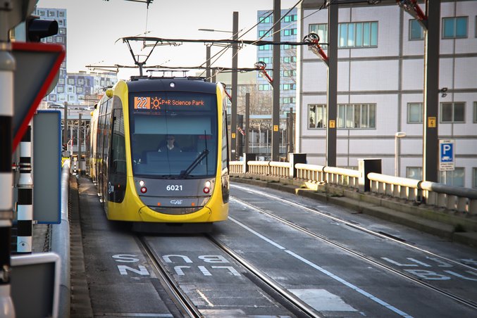 A yellow and black tram of the province of Utrecht stands at a station.