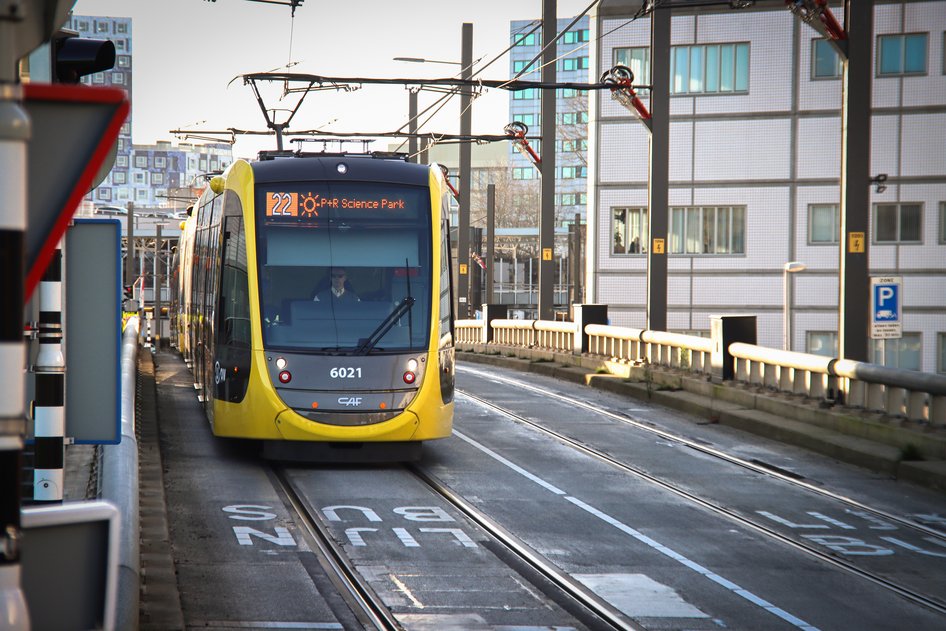 A yellow and black tram of the province of Utrecht stands at a station.