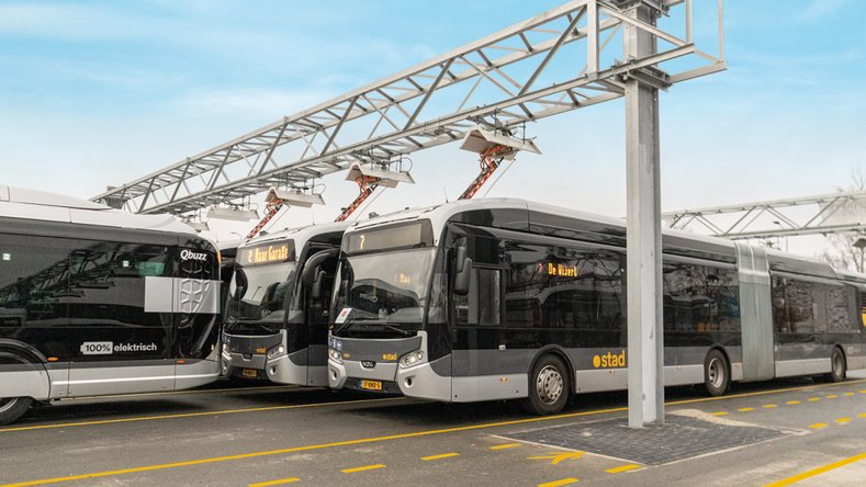 Modern articulated buses at a covered charging station – sustainable public transport infrastructure at a bus depot