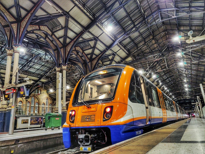 An orange Arriva Rail London train stands in a London station.