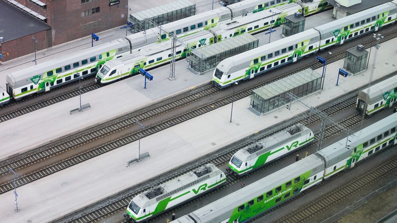 Aerial view of multiple white and green VR trains at a Finnish railway station, including a dining car and modern units