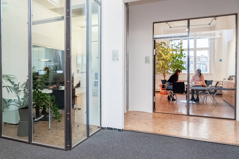 Offices with desks and green plants behind glass walls