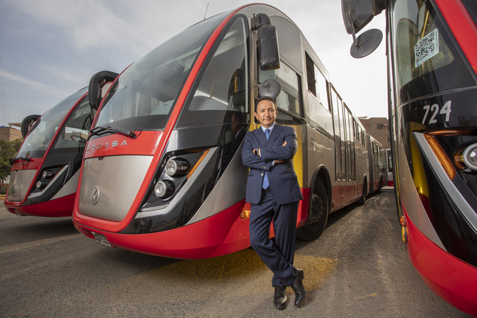 Polo Peréz, CEO of Grupo Polo, leans against a red Grupo Polo bus parked next to two other red buses in a depot.