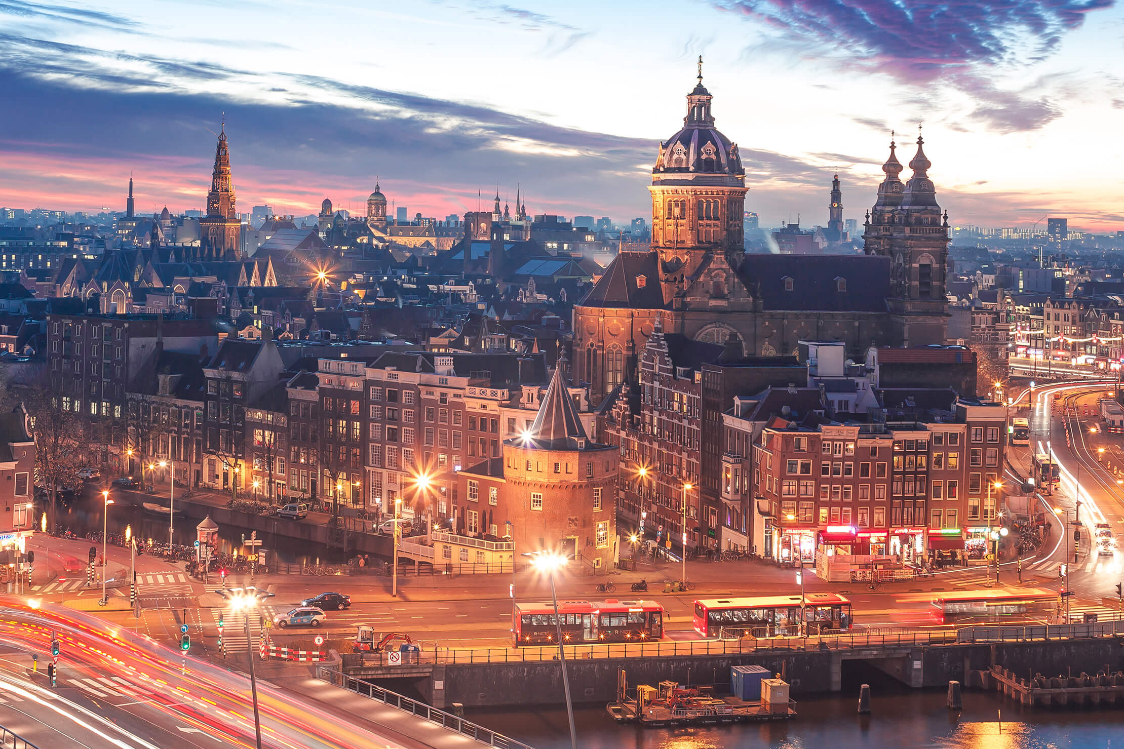Skyline von Amsterdam in der Dämmerung mit hellen Lichtern