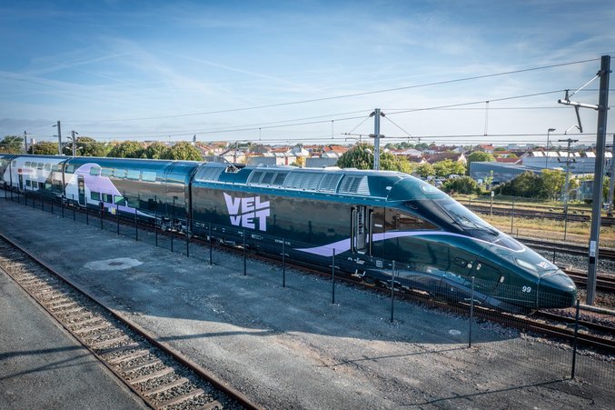 Dark blue train with VELVET lettering on tracks beneath overhead wires