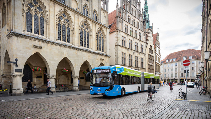 A blue bus from SWMS in front of the Münster town hall.