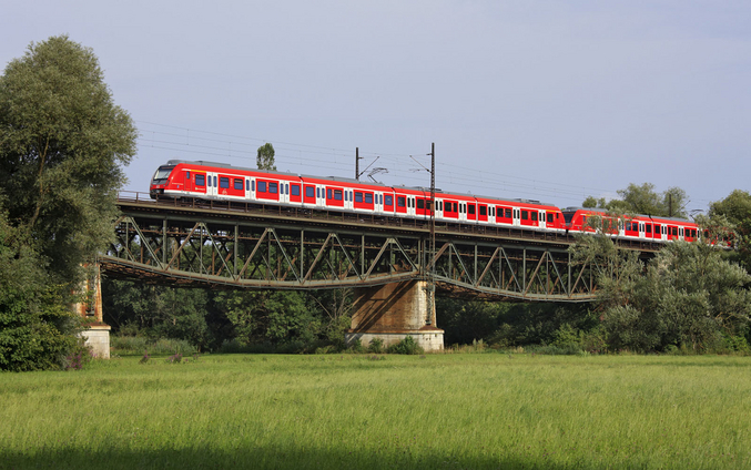 A red train from S-Bahn Stuttgart crosses a bridge outside of the city.