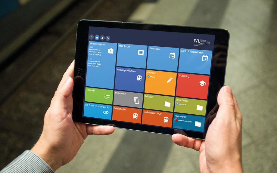 Person holding a tablet displaying a colourful tile-based user interface app.