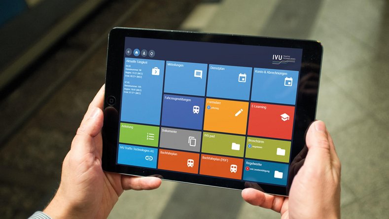 Person hält ein Tablet mit einer bunten Kachel-Benutzeroberfläche in den Händen.