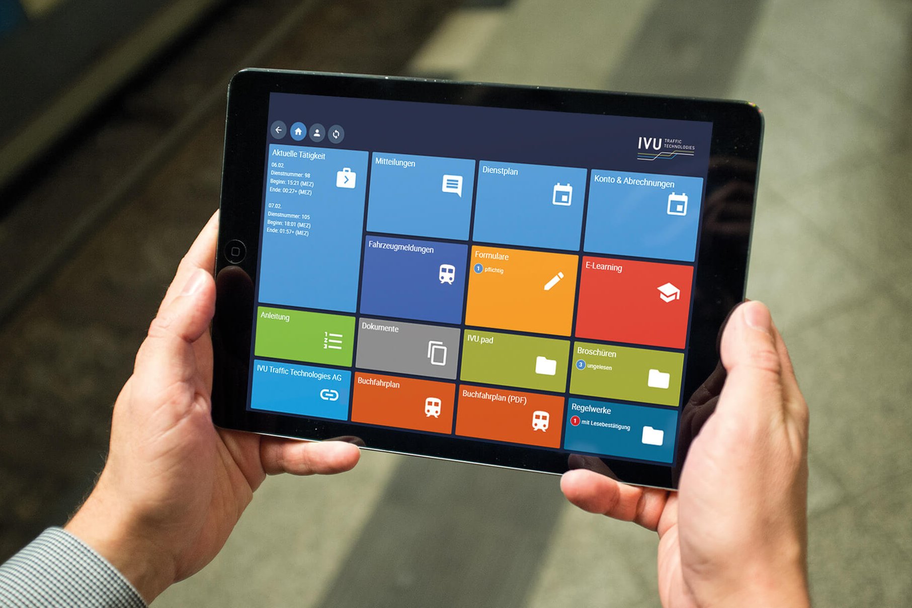 Person holding a tablet displaying a colourful tile-based user interface app.