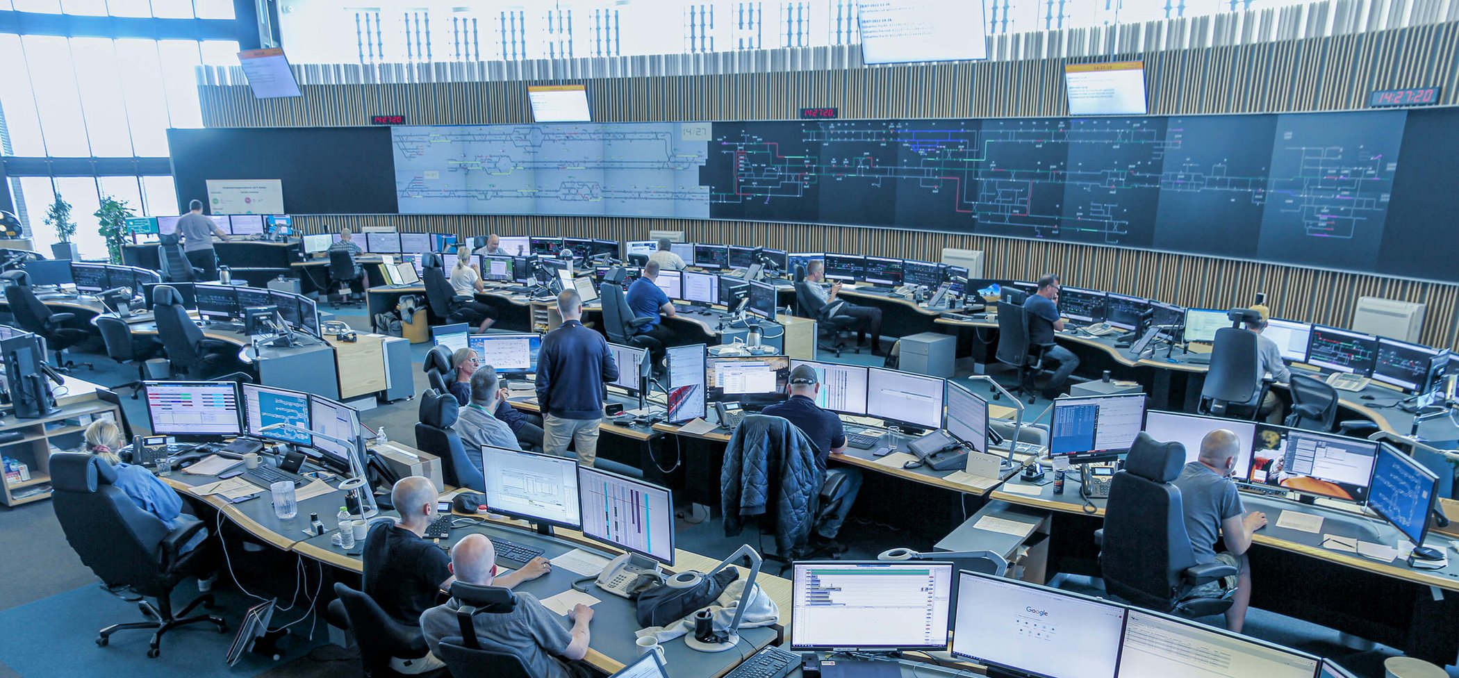 Open-plan rail control centre with numerous workstations and monitors