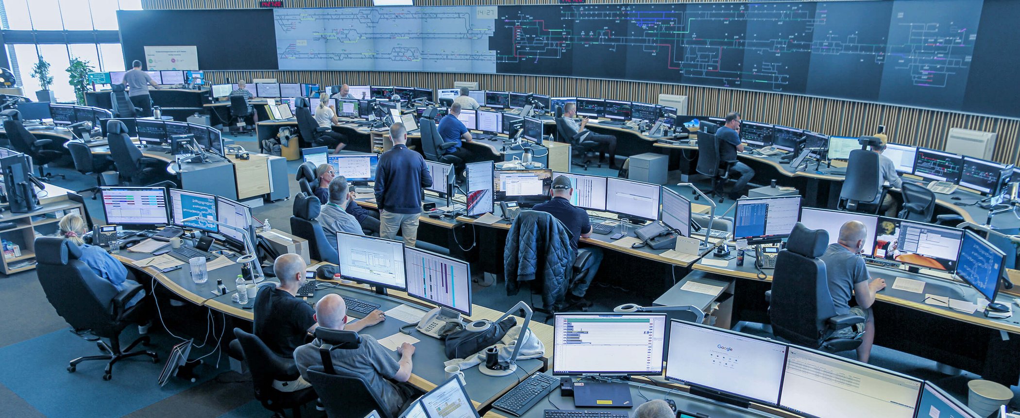Open-plan rail control centre with numerous workstations and monitors