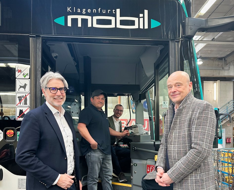 Two men standing in front of city bus with Klagenfurt mobil lettering