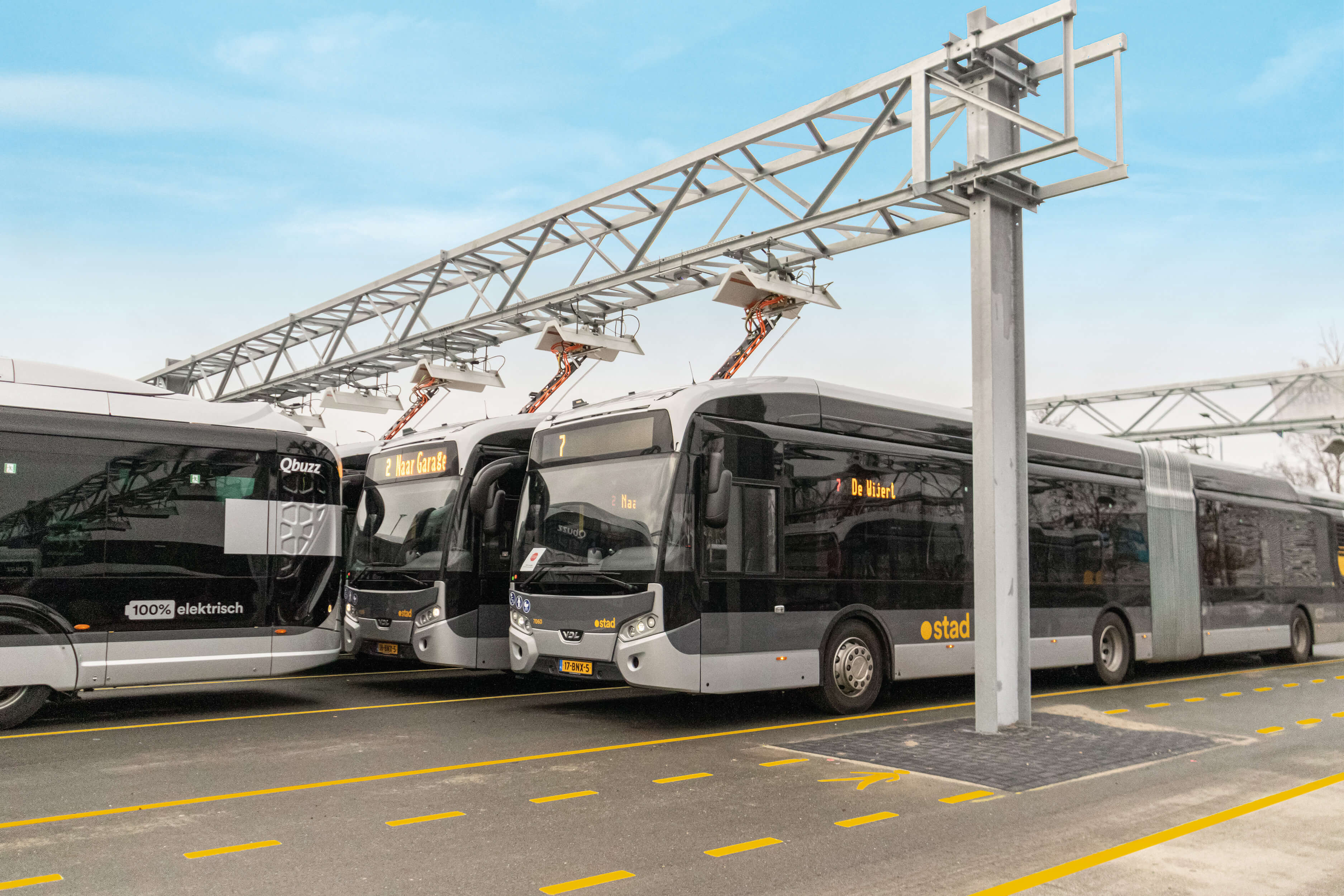 Electric buses charging under pantograph charging stations at a bus depot