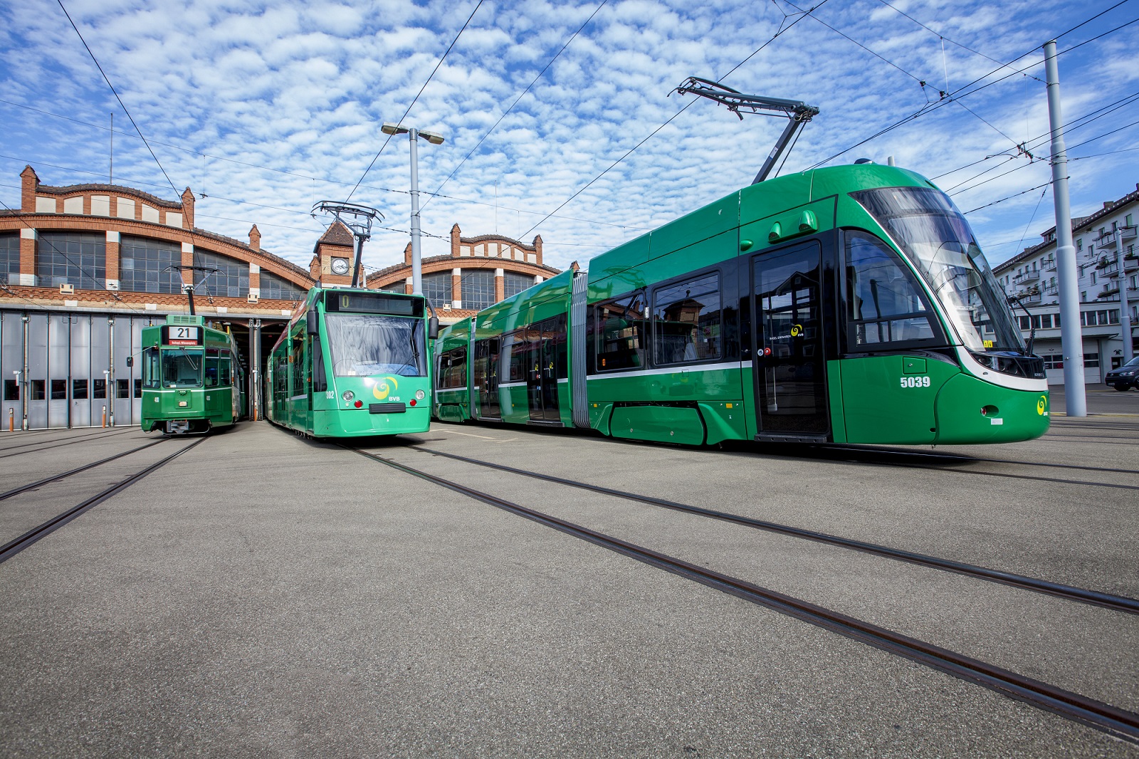 Three green BVB trams standing side by side at a depot