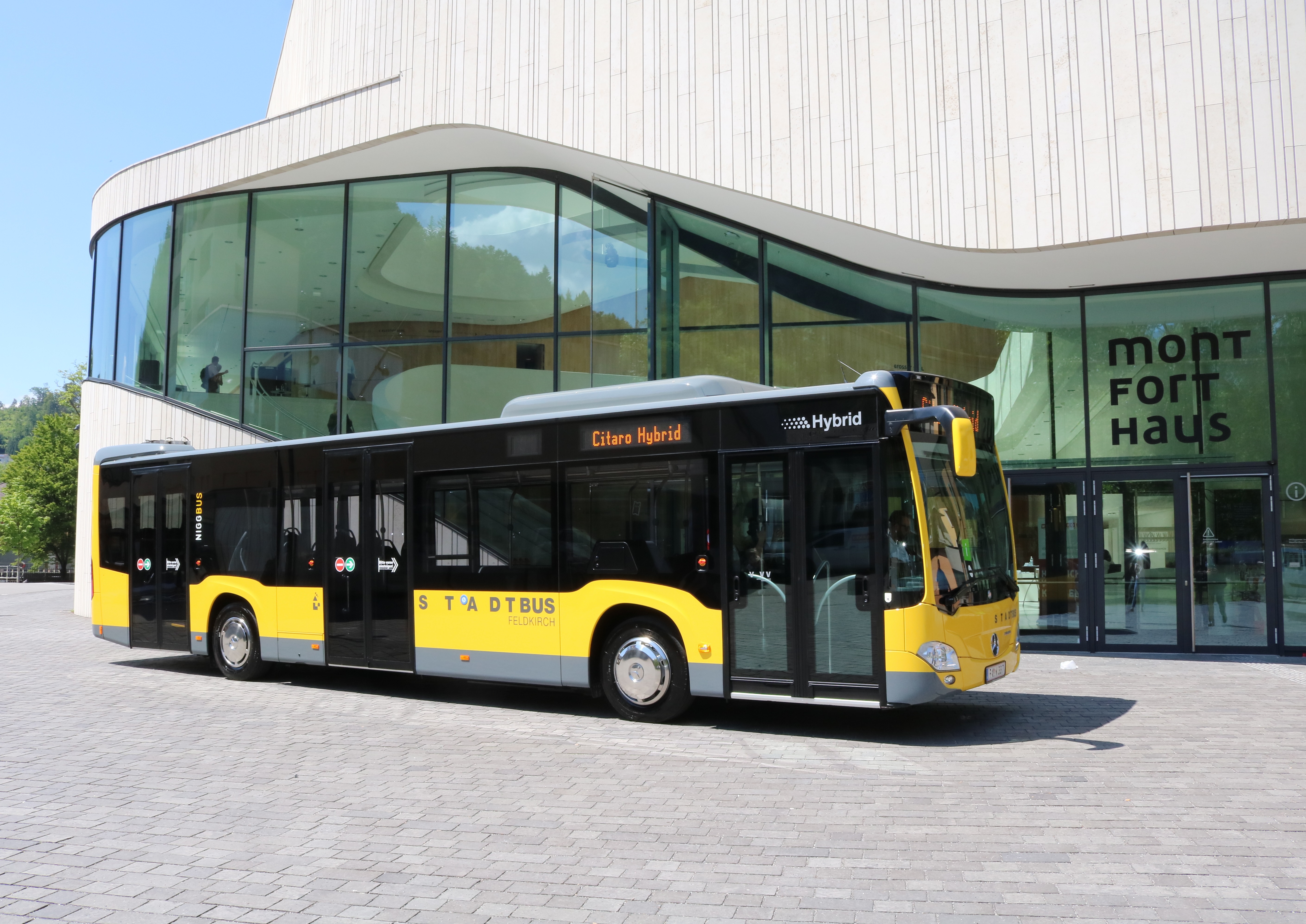 Yellow VVV bus standing in front of a modern building