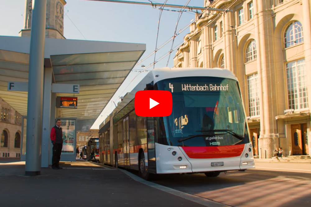 Anteprima video: autobus articolato alla fermata coperta davanti a edificio storico