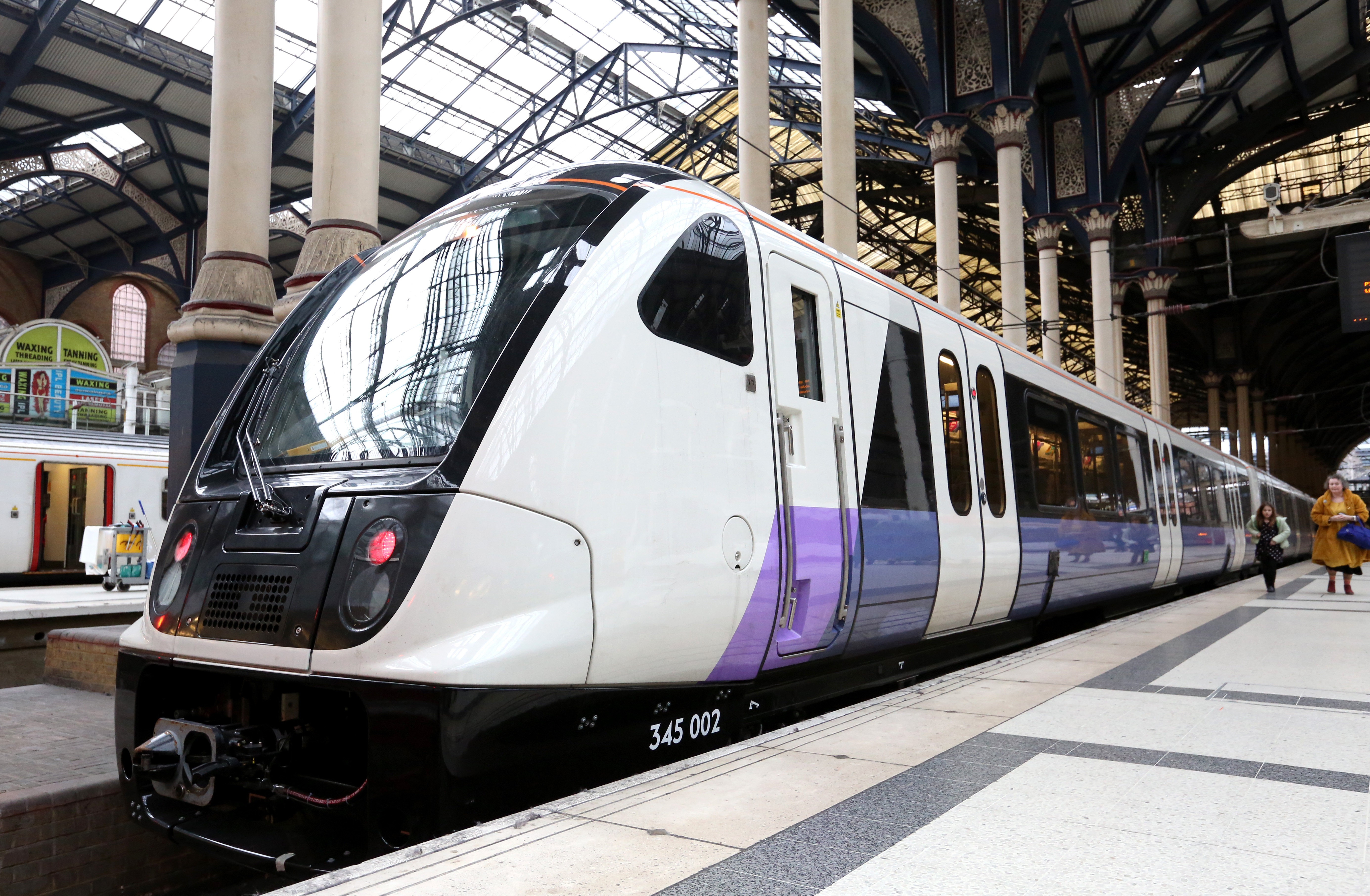 MTR Elizabeth line train in white and purple livery standing at a covered London railway station.