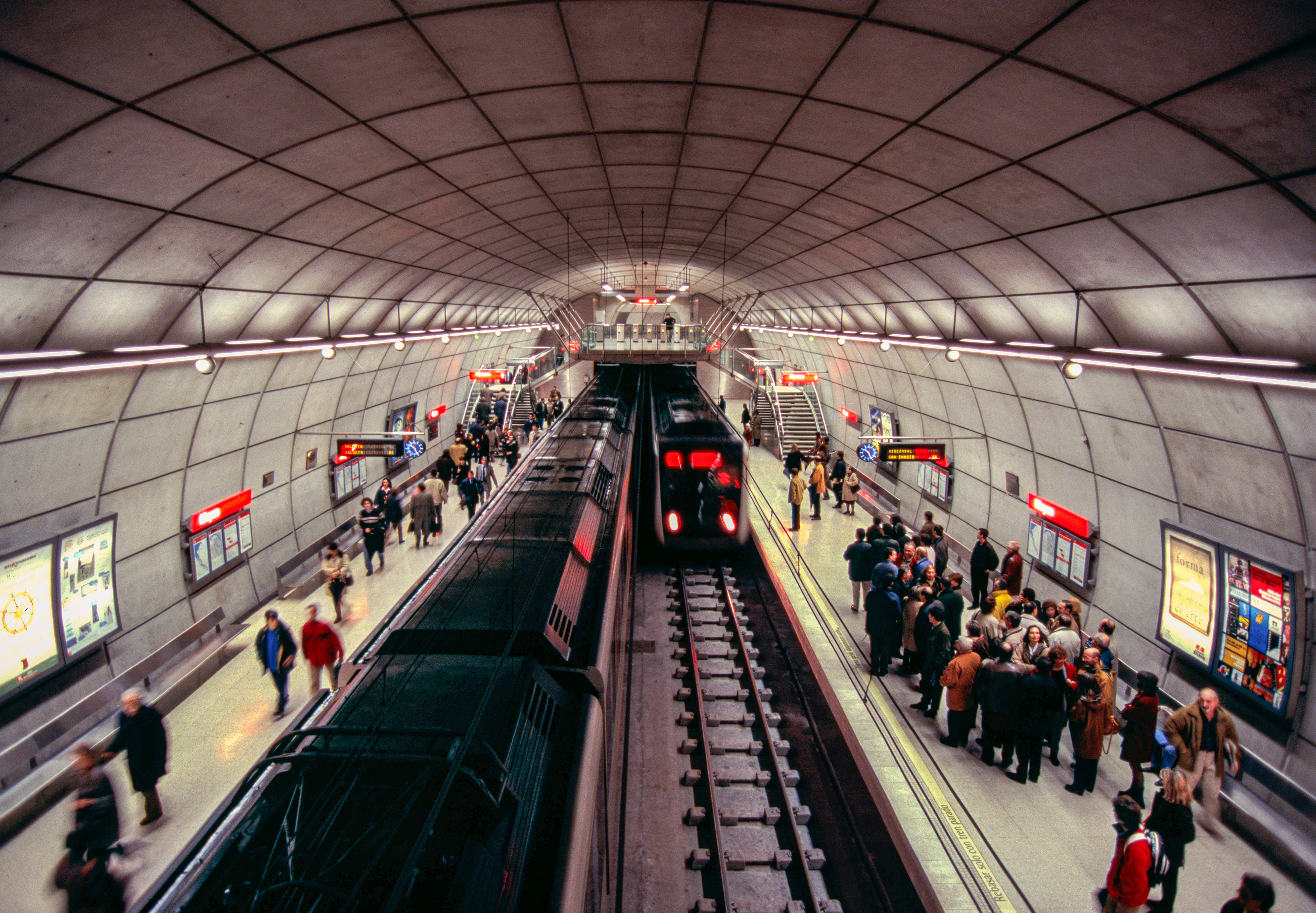 Stazione della metropolitana di Bilbao, Spagna, con treno della metro rosso e passeggeri sulla banchina